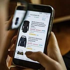 Online-Shopping Eine Person blickt auf ein Handy. Der Bildschirm zeigt einen Online-Shop.