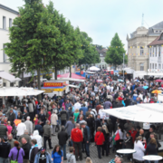 Aufnahme eines Stadtfestes mit vielen Menschen und Schirmen und Ständen in einer Fußgängerzone.